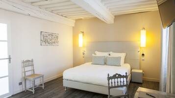 A bedroom with a large bed, two bedside lamps, a chair, a bedside table, and a small bedside table.