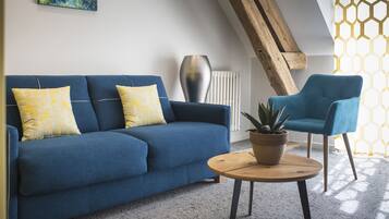 A modern living room with a blue sofa, a blue armchair, and a round wooden coffee table with a potted plant.