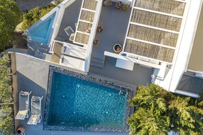 A rooftop pool area with a rectangular pool, lounge chairs, and potted plants. - The Nook (Santorini)