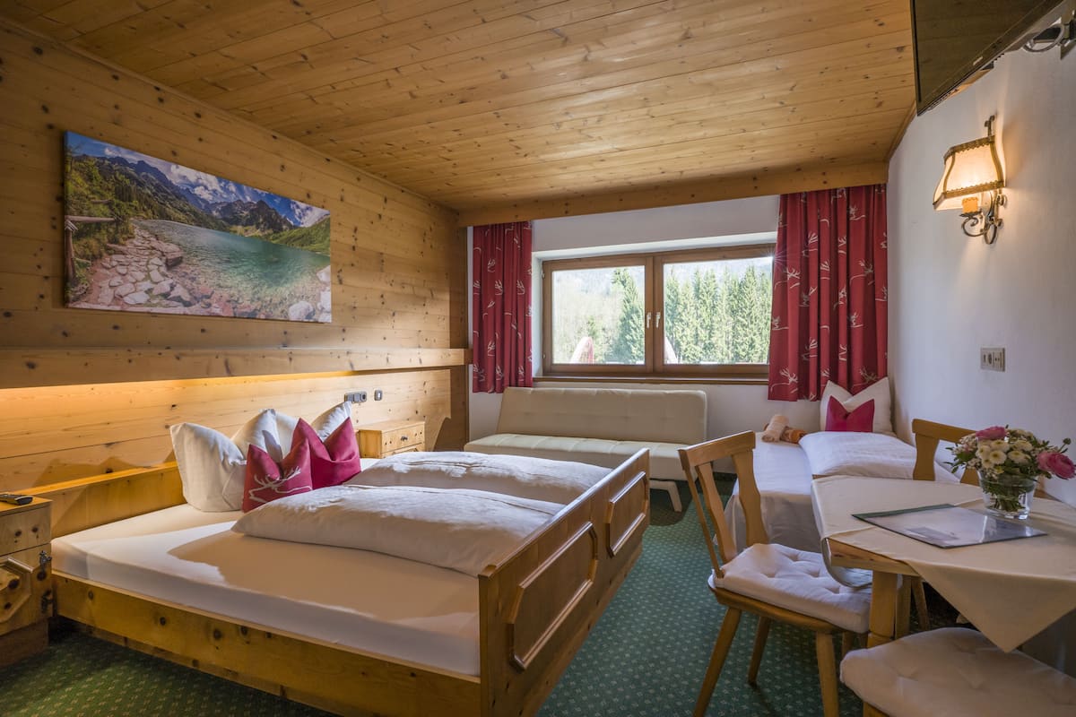 Habitación de cabaña de madera con una cama, un escritorio y una ventana con cortinas rojas.