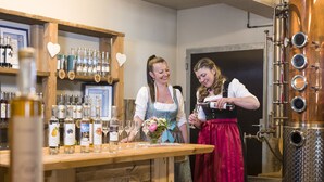 A bar area with shelves of bottles and glasses, a large copper distillation apparatus, and a wooden counter. - Pension Hüttwirt (Koessen)