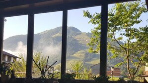 A dining area with a table set for breakfast, overlooking a mountainous landscape with a view of the sky and trees. - Pension Hüttwirt (Koessen)