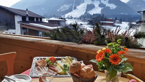 A breakfast table with a mountain view, including houses and a snow-covered peak. - Pension Hüttwirt (Koessen)