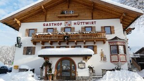 A traditional wooden building with a sign reading "GASTHOF HÜTTWIRT". - Pension Hüttwirt (Koessen)