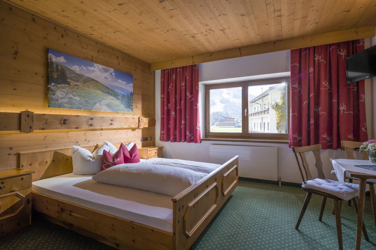 Una habitación de madera con una cama, una mesa y una silla.