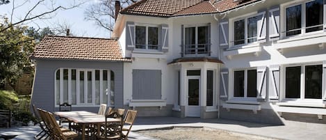 Una casa de dos pisos con un patio que incluye una mesa y sillas.