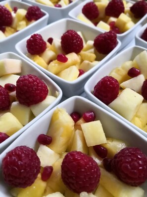 Multiple white rectangular containers filled with diced yellow fruit and red raspberries. - Brevocean (Saint-Brevin-les-Pins)