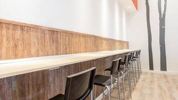 A row of bar-style seating with a wooden counter and metal chairs.