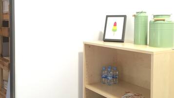 A room with a wooden shelf containing water bottles, a framed picture, and green containers.