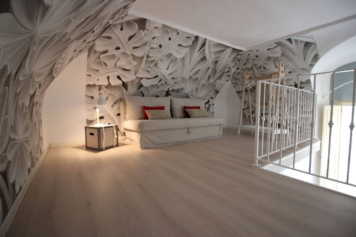 A bedroom with a large bed, a nightstand, and a decorative wall.