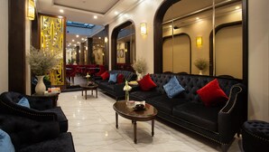 A hotel lobby with a black sofa, armchairs, a coffee table, and a decorative wall. - Flora Centre Hotel & Spa (Hanoi)