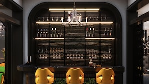 A bar area with a black marble wall, a chandelier, and three yellow chairs. - Flora Centre Hotel & Spa (Hanoi)