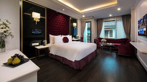 A modern hotel room with a large bed, a red sofa, a small table, and a TV. - Flora Centre Hotel & Spa (Hanoi)