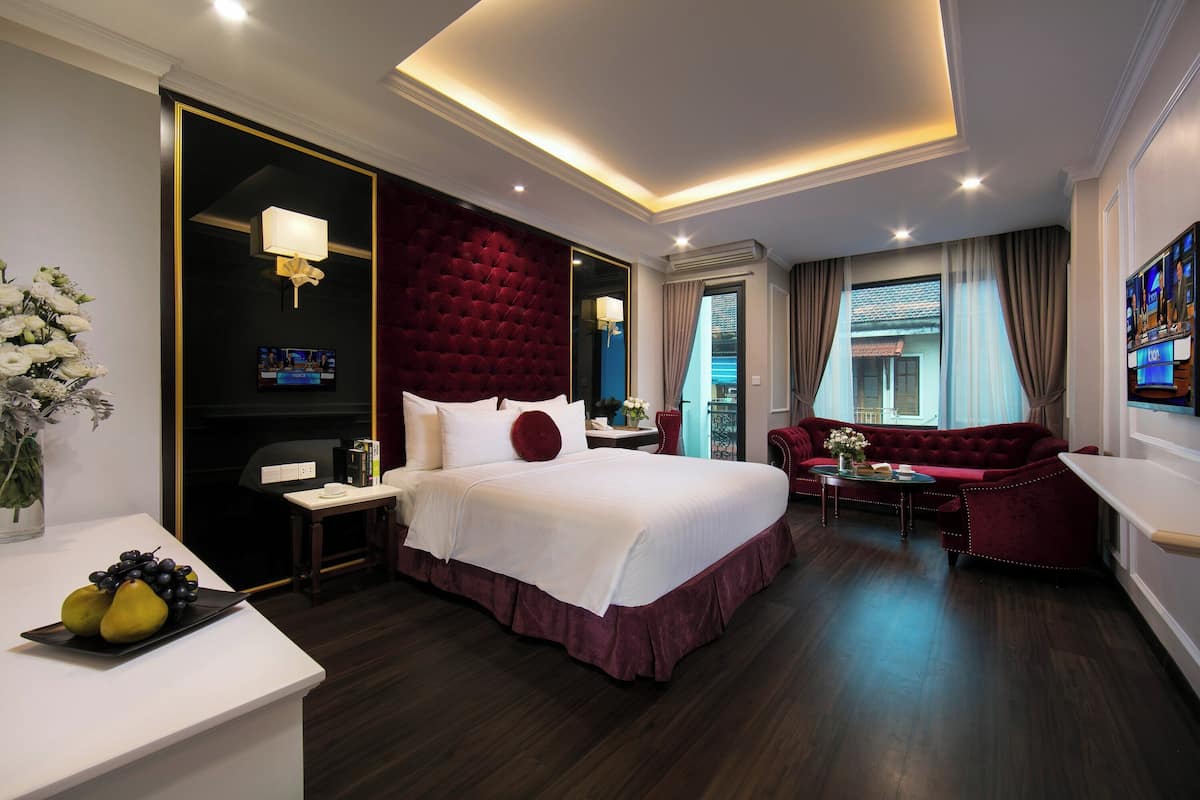 Een moderne hotelkamer met een groot bed, een rode bank, een tafeltje en een televisie.