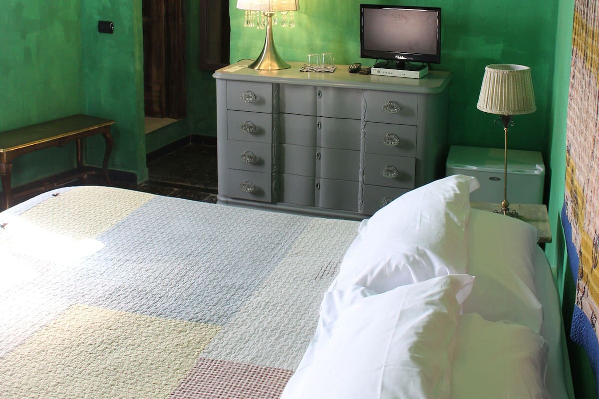 A room with a bed, a dresser, a television, and a lamp.
