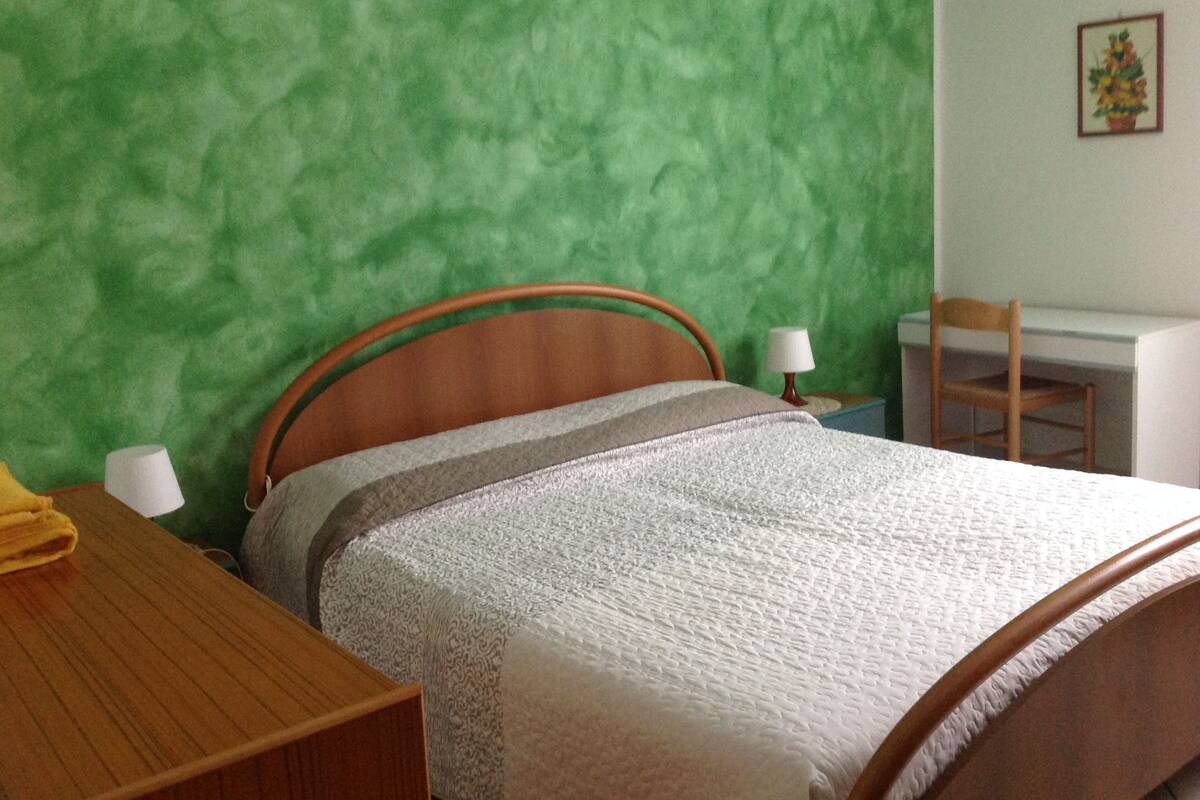 Una habitación con una cama, un escritorio y una silla.