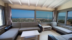 Una sala de estar moderna con un amplio ventanal que ofrece vistas a la ciudad, un sofá seccional, una mesa de centro y una mesita.