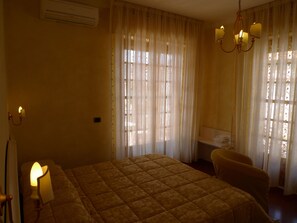 A hotel room with a bed, a chair, a desk, and a chandelier. - B&B Il Nido (Ricadi)