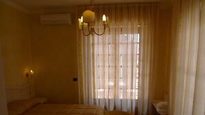 A hotel room with a bed, a chair, a nightstand, and a window with curtains. - B&B Il Nido (Ricadi)