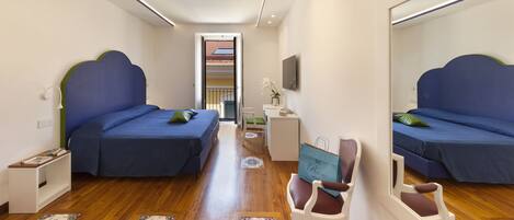 A bedroom with two beds, a desk, a chair, and a mirror.