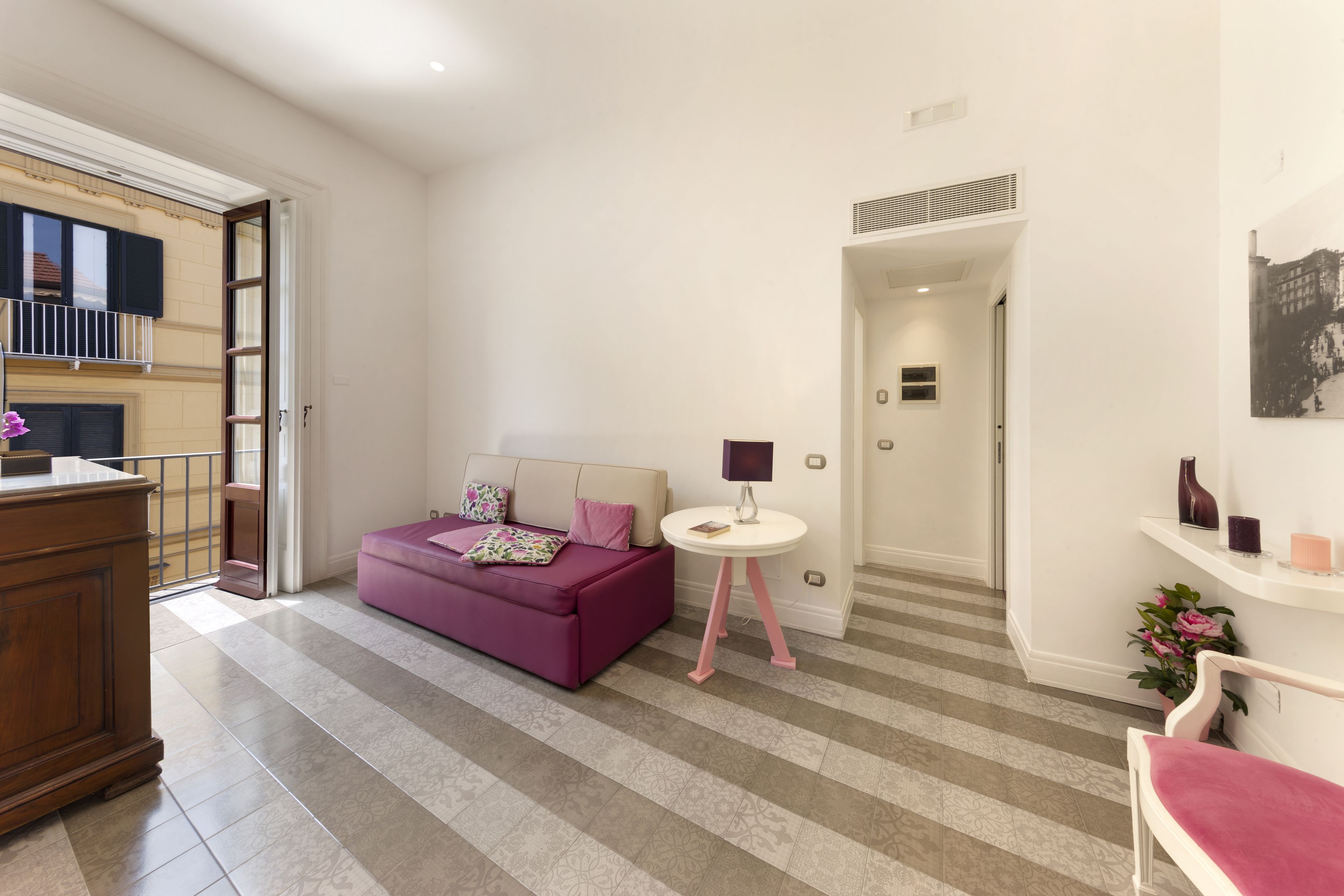 A modern living room with a purple sofa, a small round table, and a white chair.
