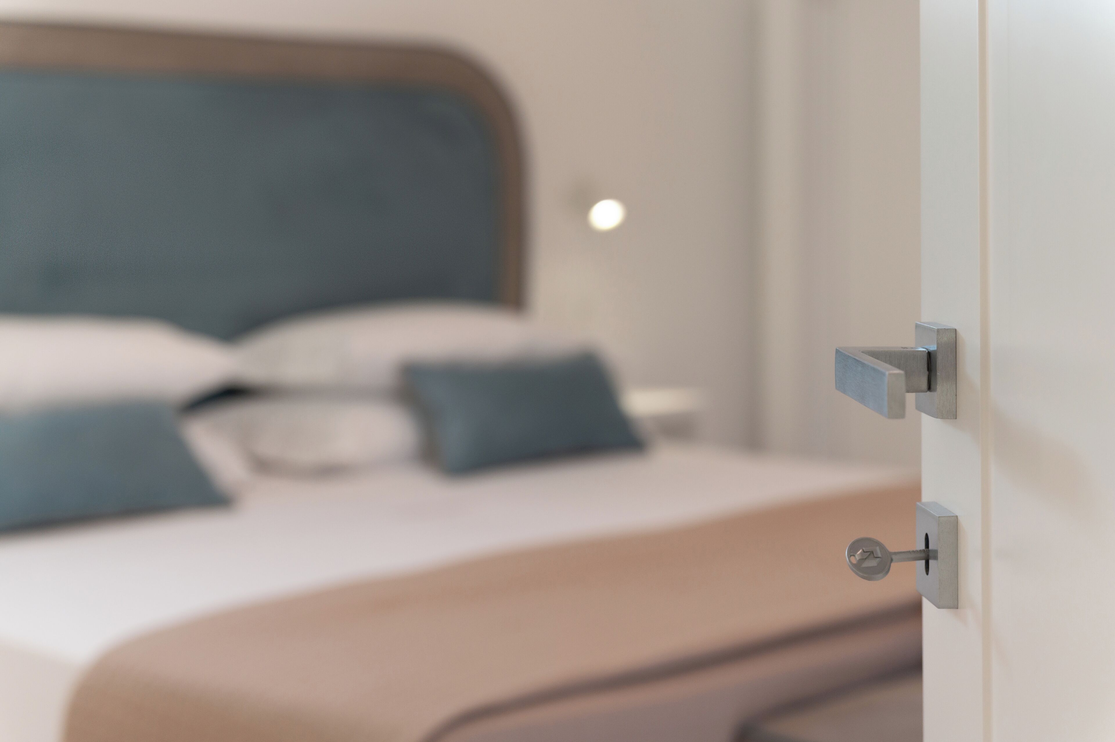 A bedroom with a bed, pillows, and a door with a lock.