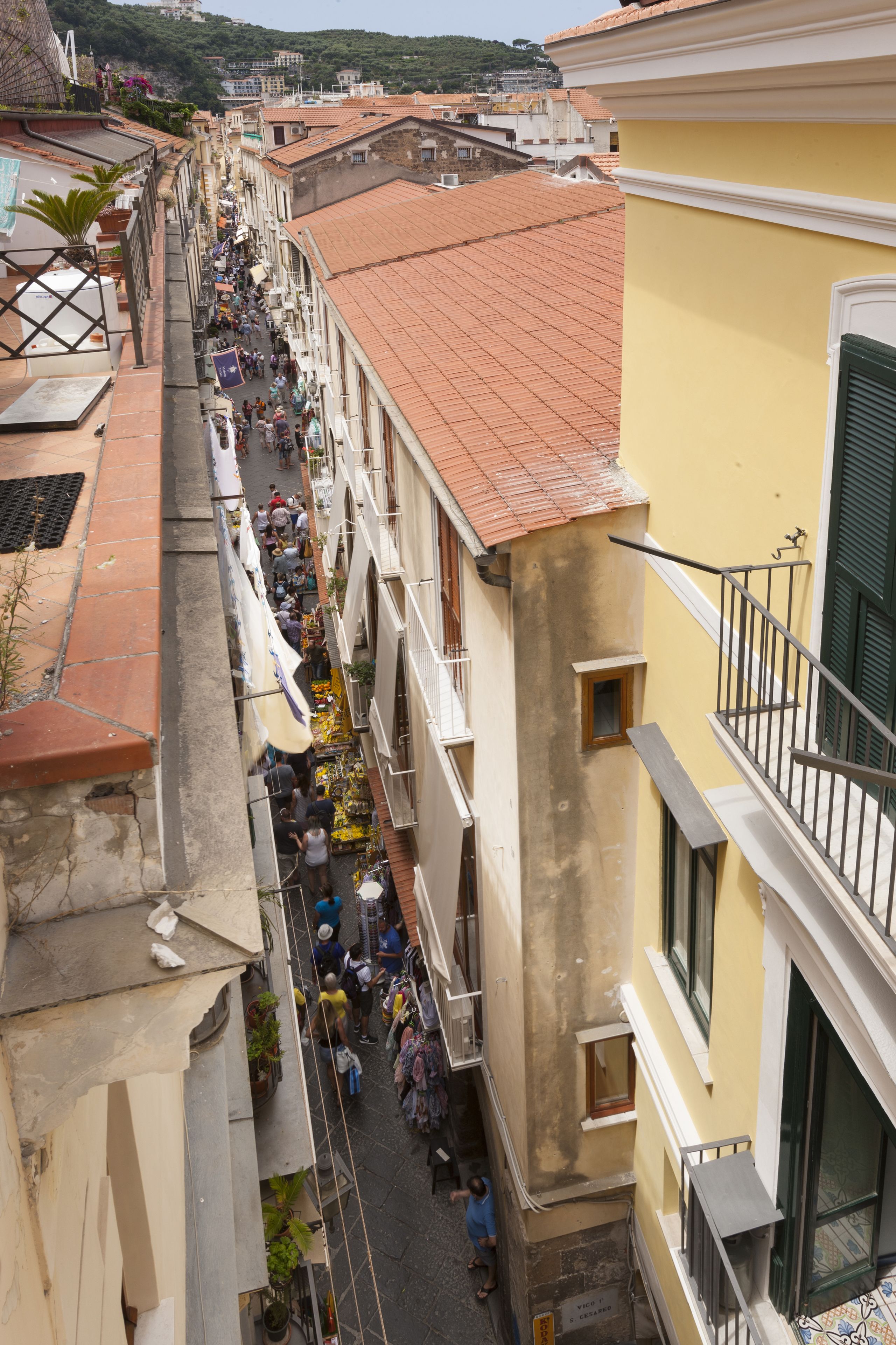 A narrow street lined with buildings, a crowd of people, and a variety of shops.