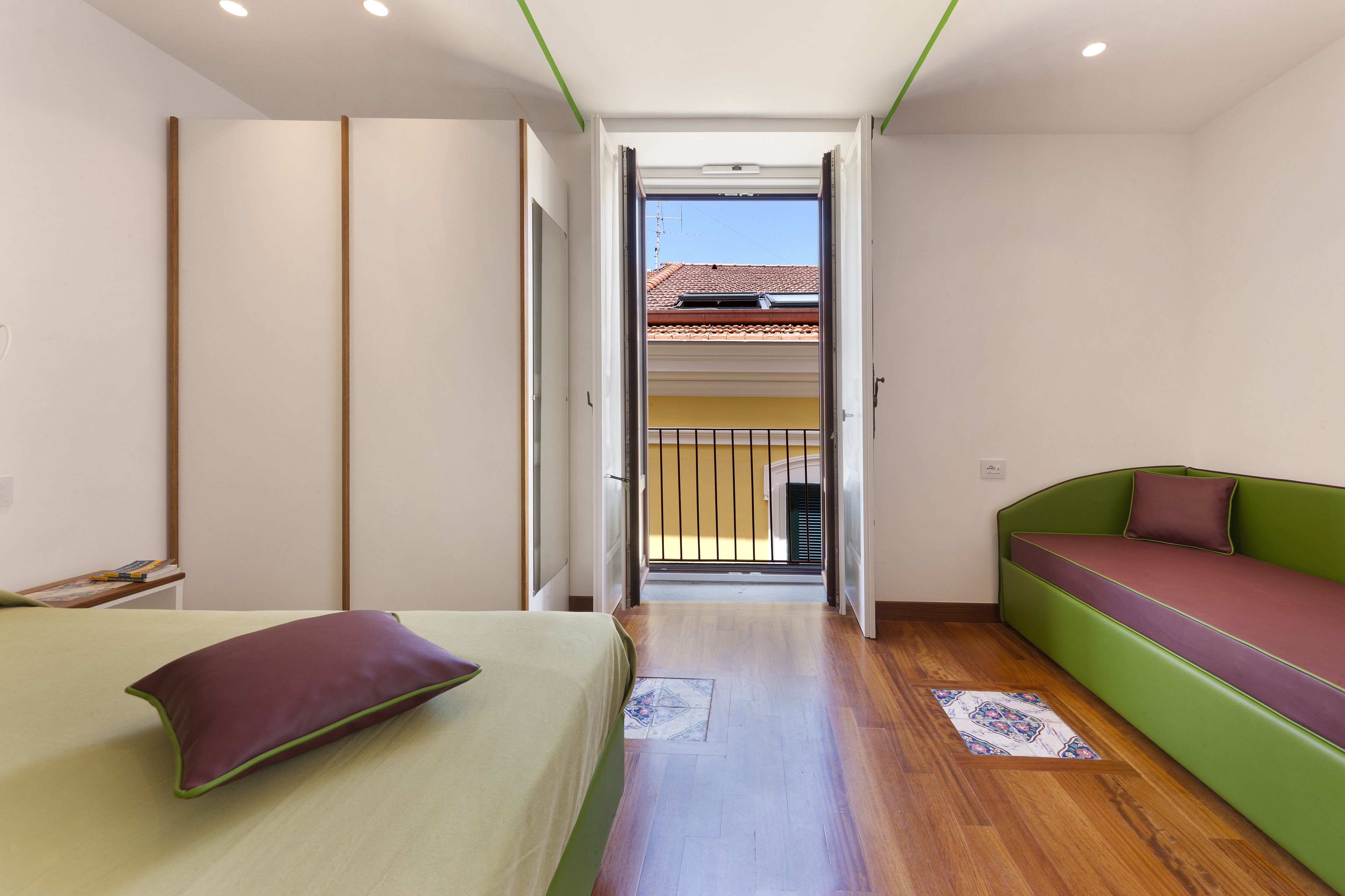 Un dormitorio con una cama, un sofá verde y vistas a un balcón.