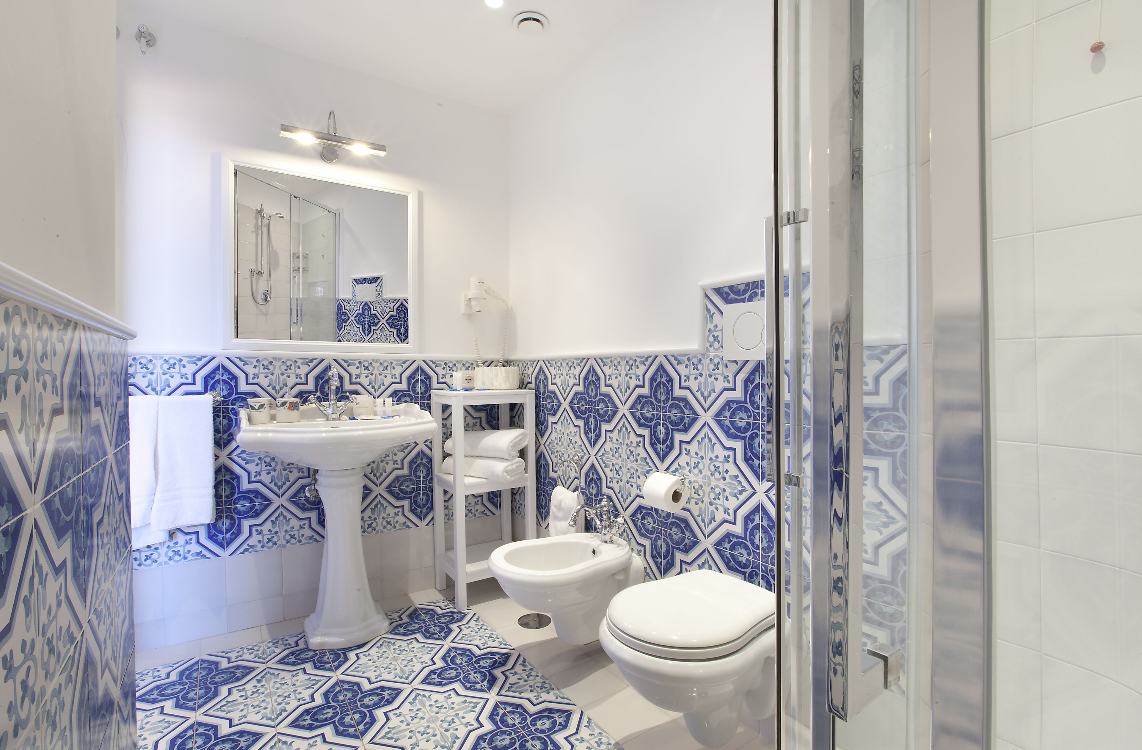 A bathroom with a pedestal sink, a toilet, and a shower area.
