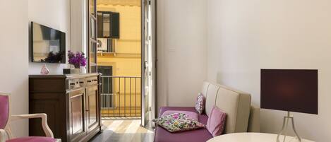 A hotel room with a bed, a chair, a desk, a lamp, and a view of the outside.