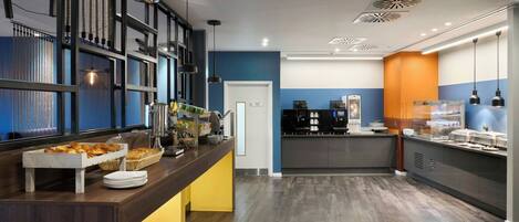A modern kitchen area with a buffet setup, including a bread station and various food items.