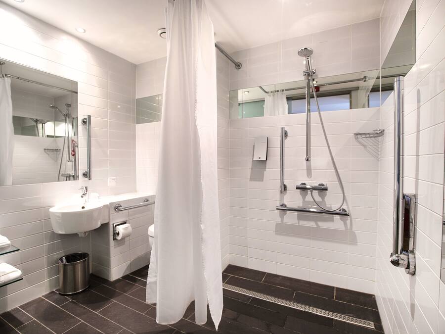 A modern bathroom with a glass shower enclosure, a white sink, and a mirror.