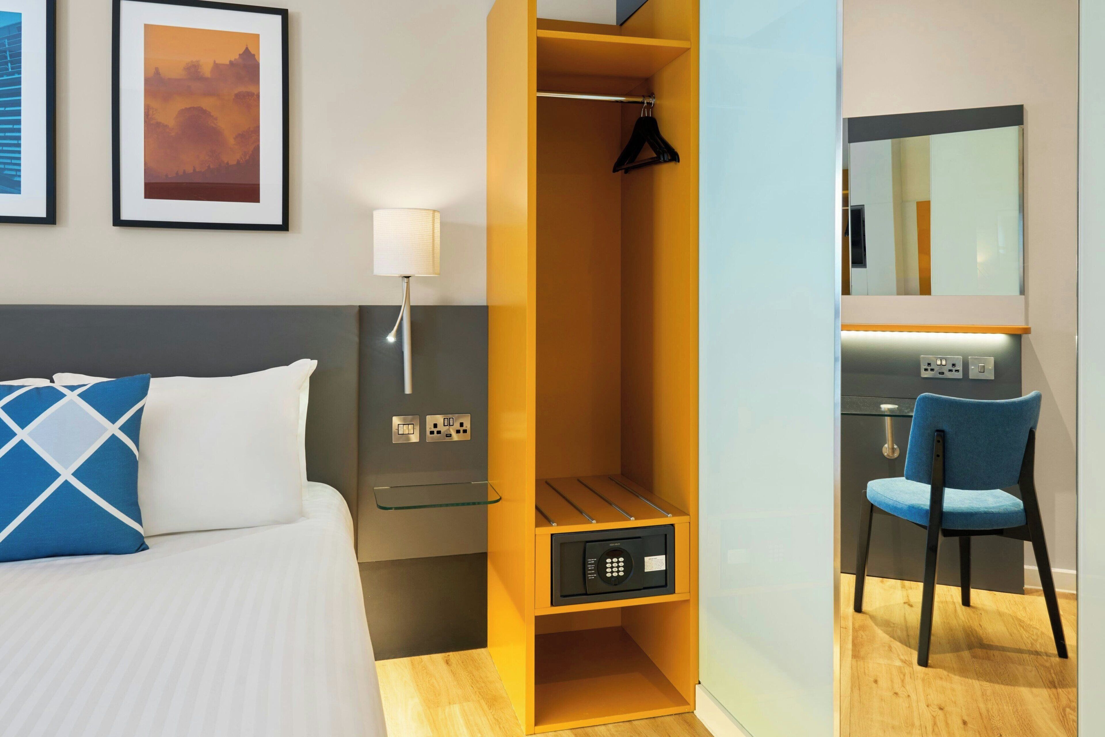 A hotel room with a bed, a wardrobe, a desk, and a chair.