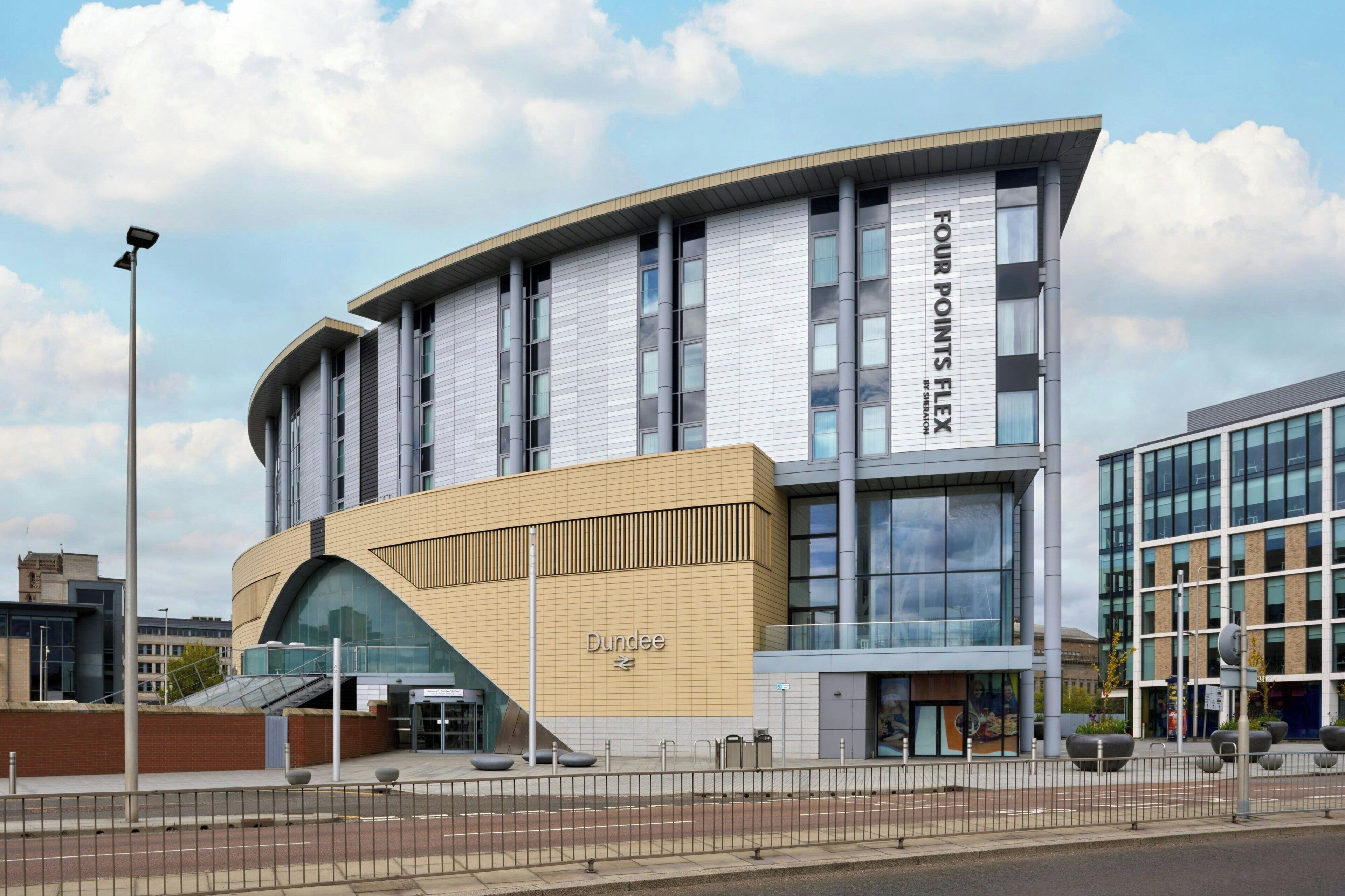 A modern building with a curved facade, a prominent 'Four Points Flex' sign, and the word 'Dundee' on the lower part.