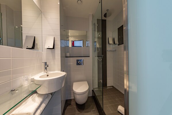 A modern bathroom with a glass shower enclosure, a white sink, and a toilet.