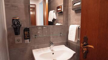 Ein Badezimmer mit Waschbecken, Handseifen-Spender, Seifenschale aus Glas und Handtuchhalter.