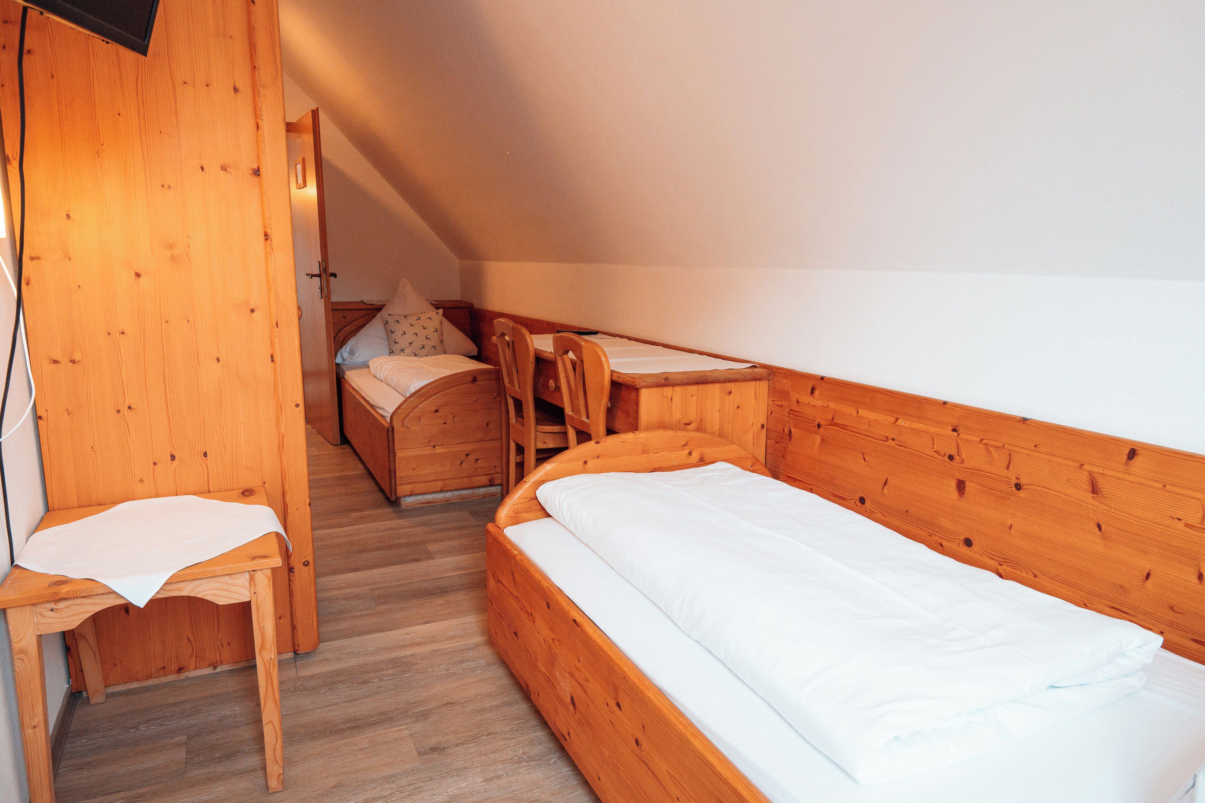 Una habitación de madera con una cama individual, una silla y un escritorio.