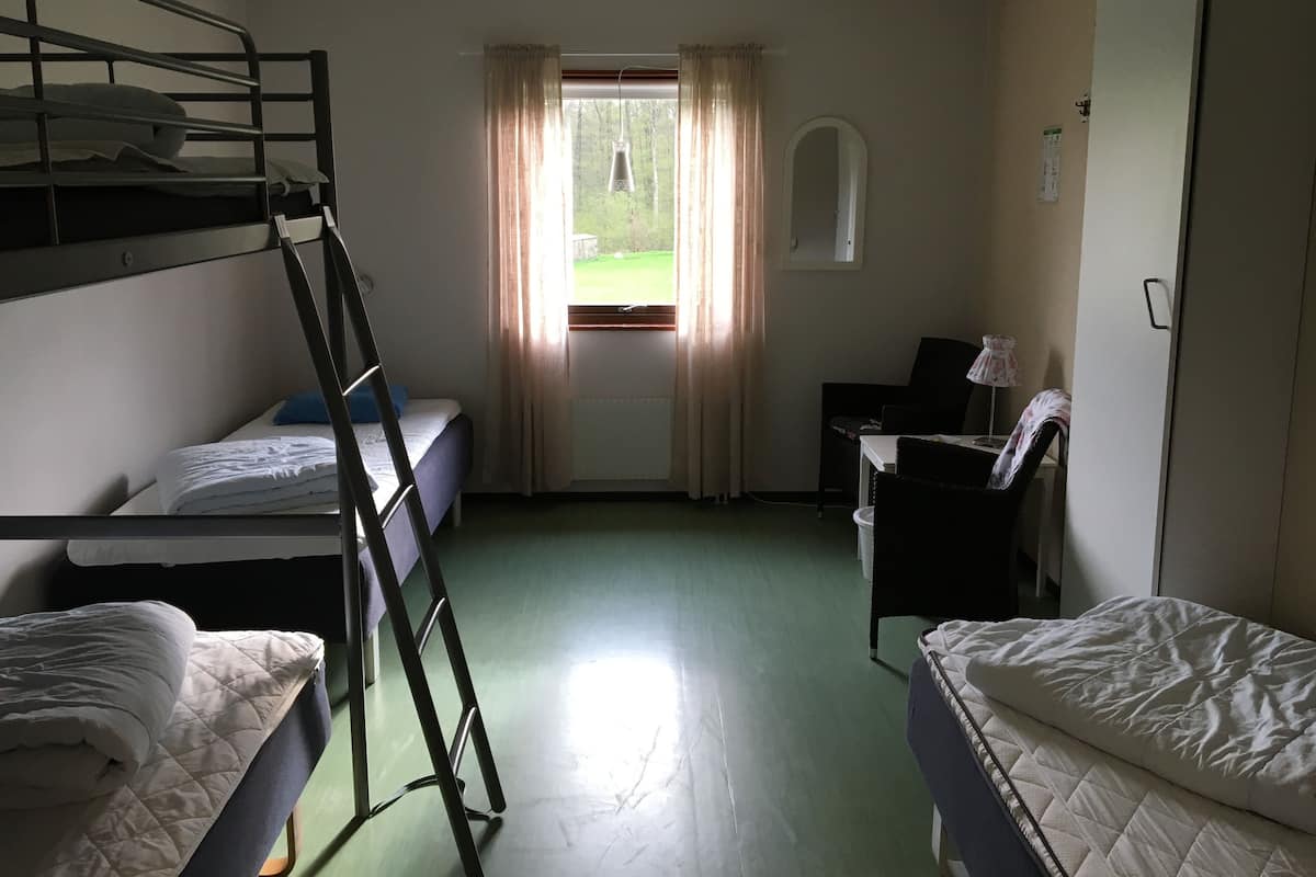 Une chambre de dortoir avec des lits superposés, un bureau, une chaise, une lampe et une fenêtre avec des rideaux.