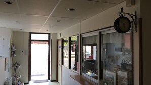 A hallway with a reception desk, a clock, and a window with a view of the outside.