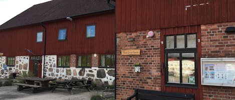 A red wooden building with a stone facade, a wooden bench, and a picnic table outside.