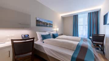 A hotel room with a bed, a desk, a chair, a telephone, and a painting on the wall.