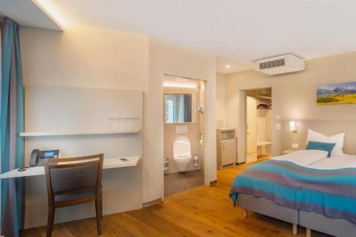 A hotel room with two beds, a desk, and a bathroom.