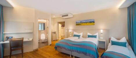 A hotel room with two beds, a desk, and a bathroom.