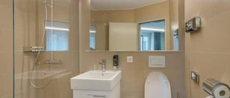 A modern bathroom with a glass-enclosed shower, a white sink, and a toilet.