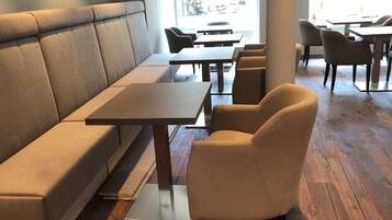 Un intérieur de restaurant moderne avec un long banc servant de siège, des tables individuelles et un plancher en bois.