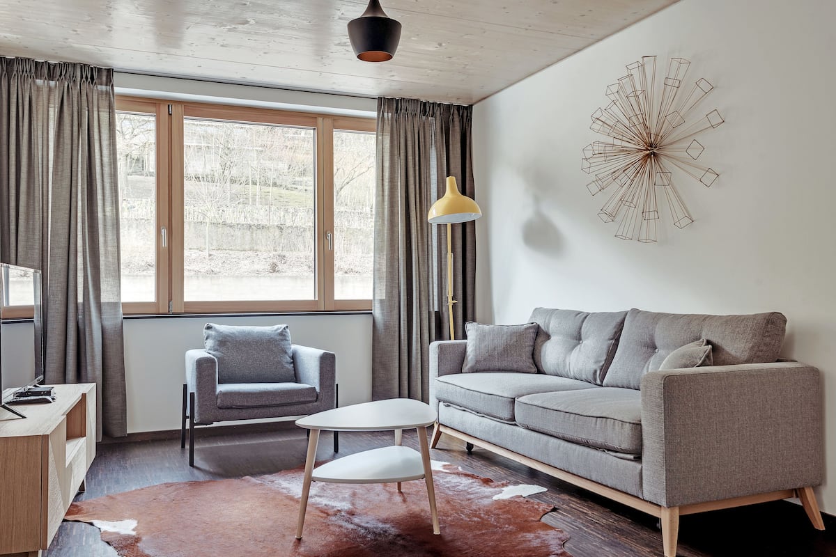A modern living room with a grey sofa, a small white table, and a cowhide rug.
