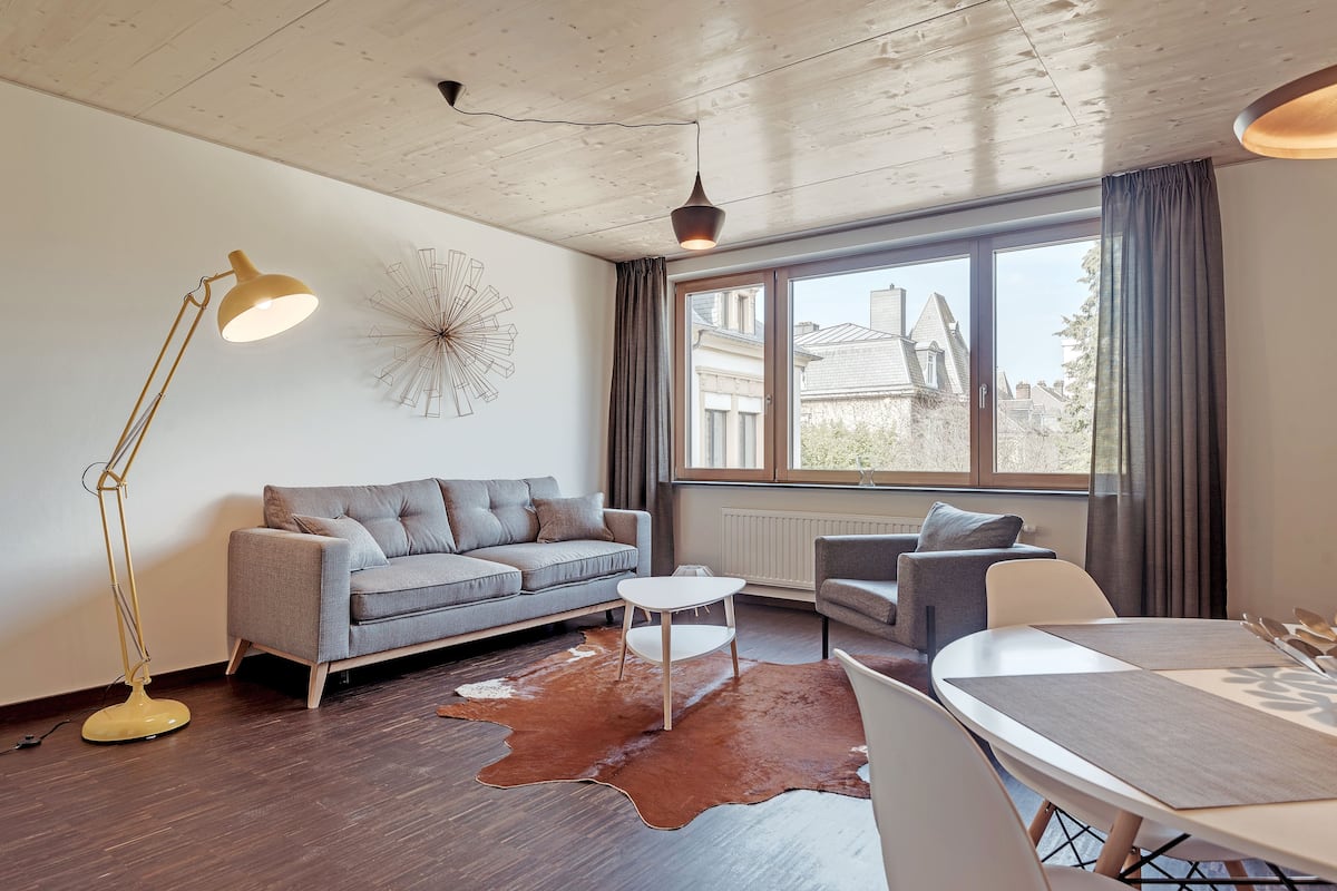 A modern living room with a sofa, coffee table, and dining table.
