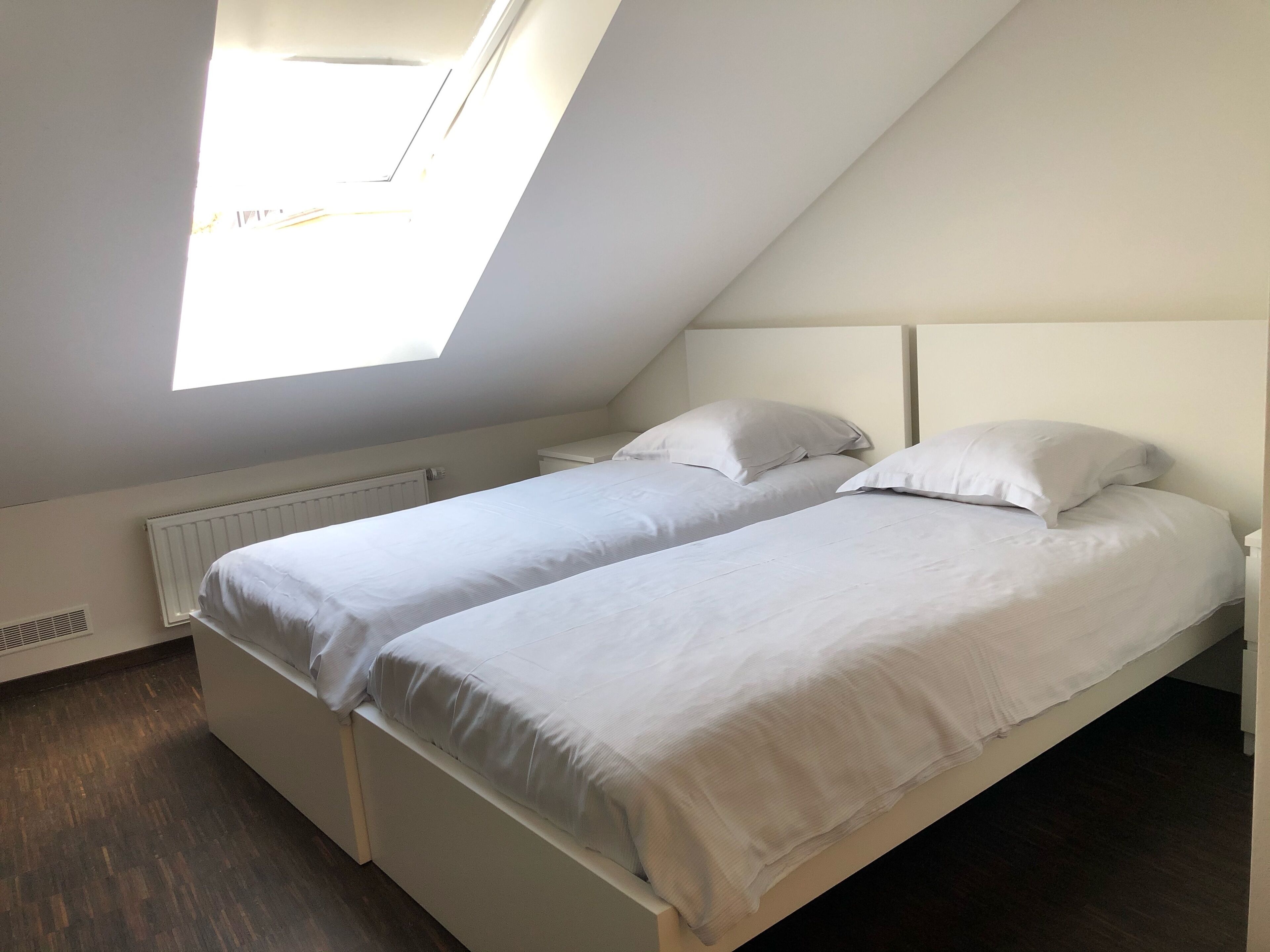 Ein Doppelzimmer mit zwei Betten, einem Dachfenster und einer Heizung.