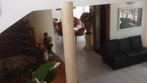 A living room with a black sofa, a dining area with red chairs, and a staircase leading to another level. - Hotel Mutacita (Rimini)