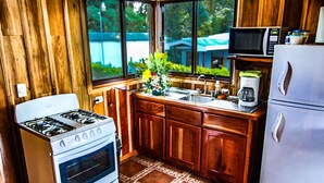 Une cuisine de taille réduite, dotée de meubles en bois, d’une cuisinière à gaz, d’un évier, d’un four à micro-ondes et d’un réfrigérateur.
